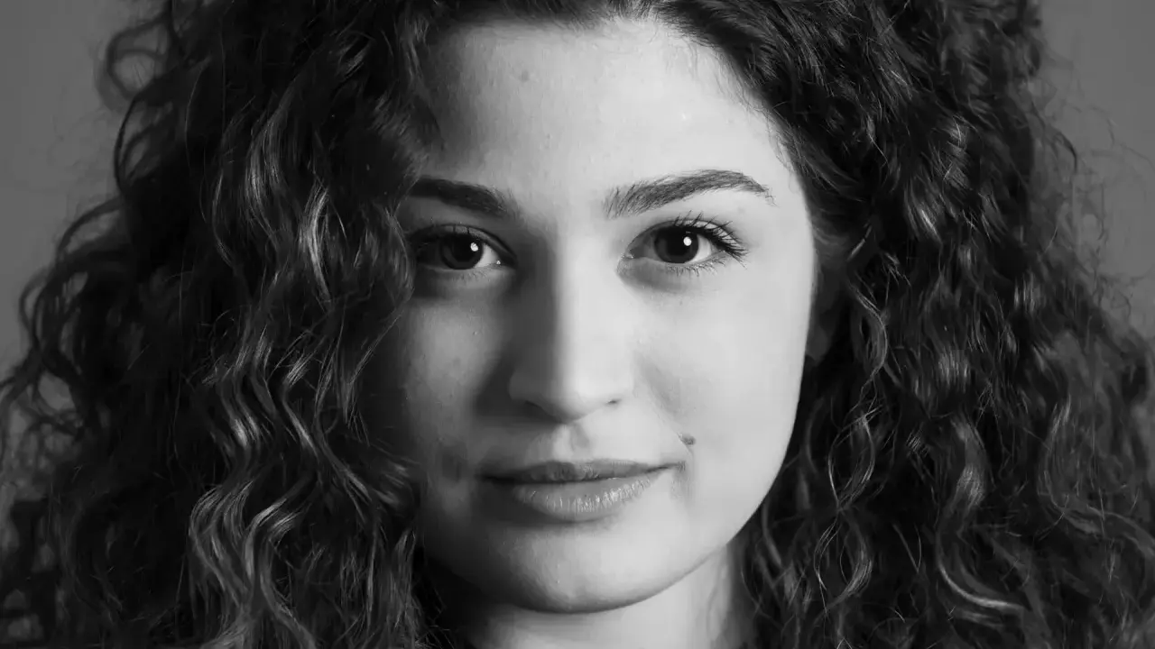 Primo piano di una giovane donna con capelli ricci, un esempio di diversi tipi di ritratto che catturano espressioni uniche.