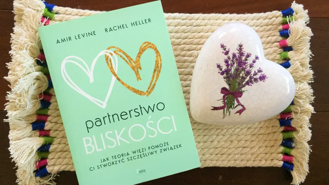 Książka "Partnerstwo bliskości. Jak teoria więzi pomoże Ci stworzyć szczęśliwy związek" obok serca z lawendą.