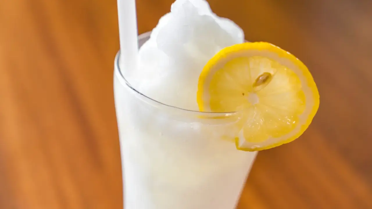 Un refrescante granizado de limón, coronado con una rodaja de limón, perfecto para un día caluroso.