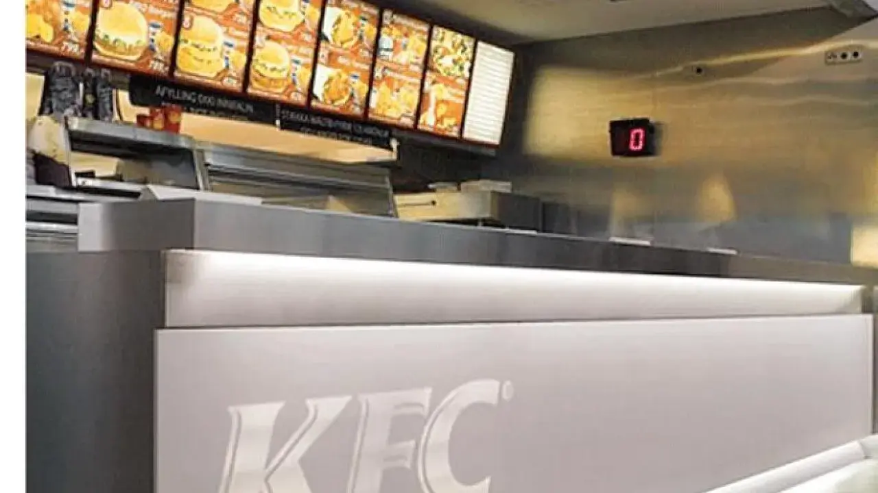 Mostrador de KFC con menú digital y cartel de "0". El food court significado es un área de comida.