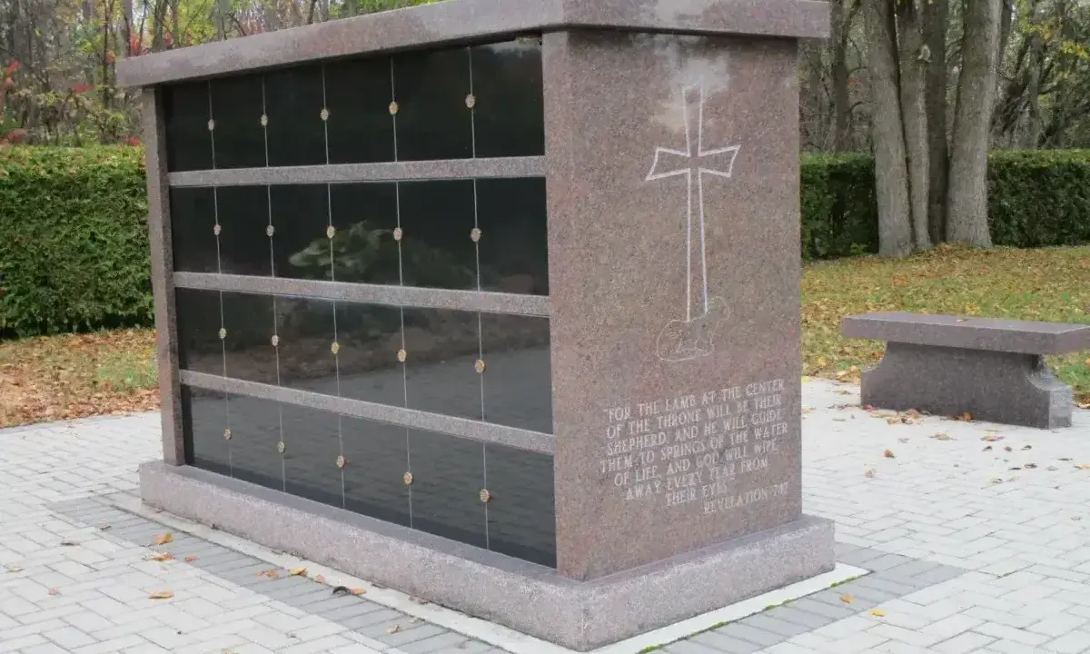 Mauzoleum z miejscami na urny, symbolizujące jak wygląda pochówek urny. Kamienna ławka obok.