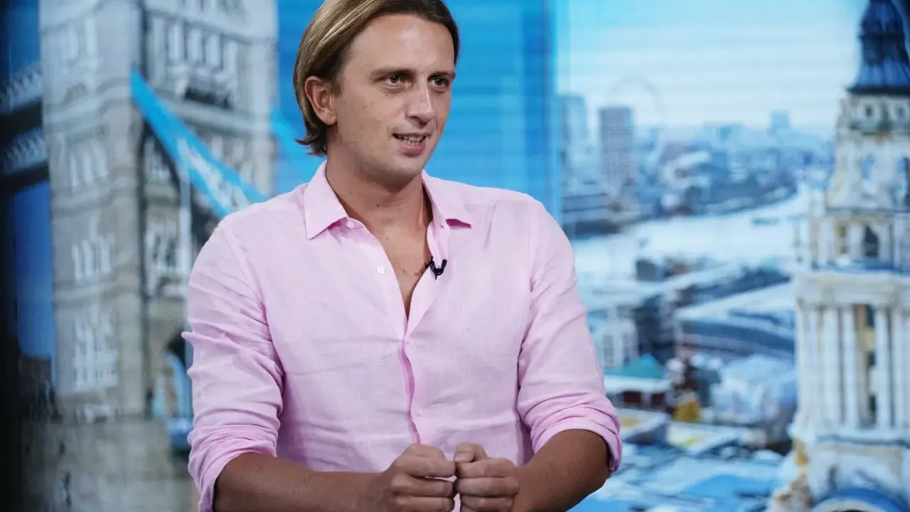 Nikołaj Storonski w różowej koszuli, na tle panoramy Londynu z Tower Bridge.