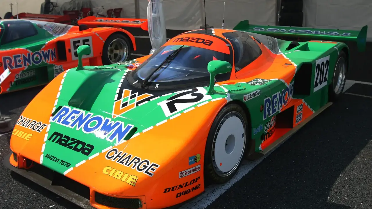 El icónico Mazda 787B, con su distintivo diseño naranja y verde, listo para la carrera.