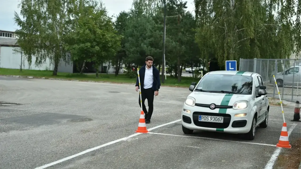 Egzamin praktyczny w WORDzie: młody mężczyzna ustawia pachołek na placu manewrowym obok białego Fiata Panda z literą L.