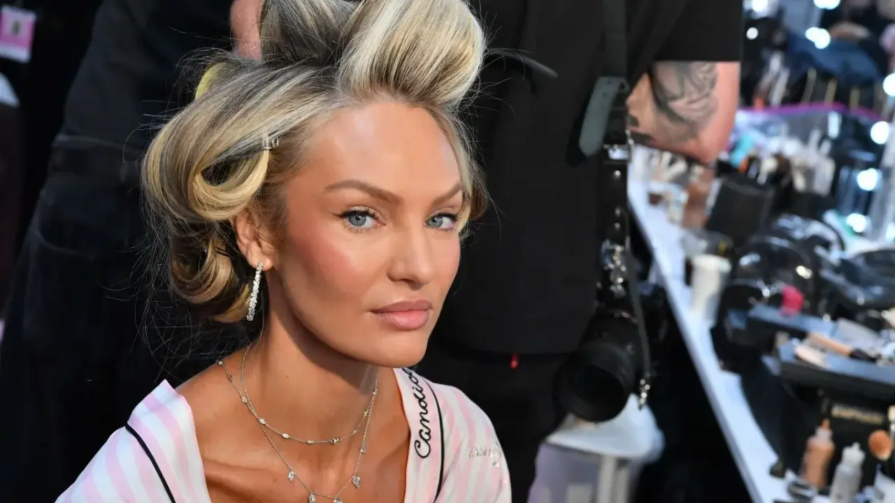 Blond włosy modelki w lokach, delikatny air touch. W tle wizażystka i kosmetyki.