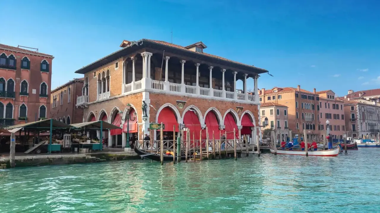 Le marché du Rialto à Venise, avec ses étals colorés et ses gondoles sur le Grand Canal.