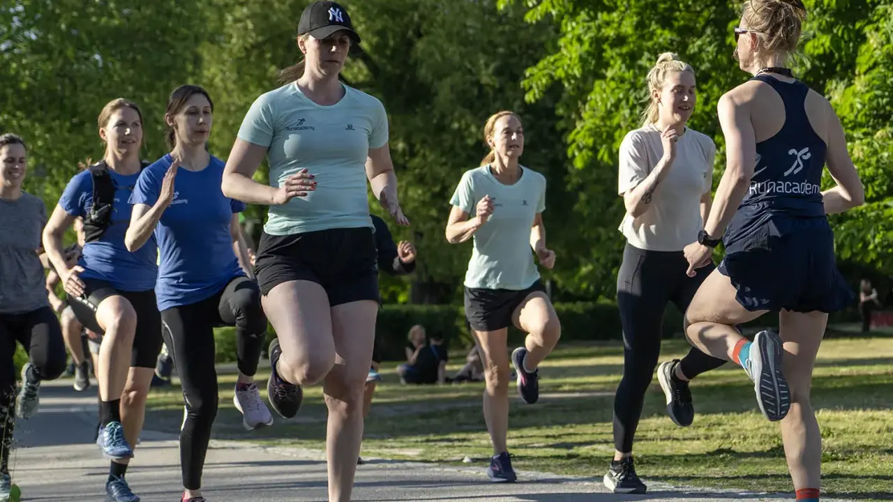 Grupp kvinnor tränar löpning i parken, ett intensivt backintervaller pass.