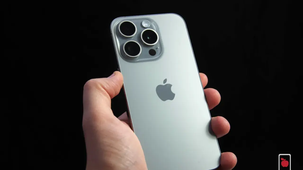 Dłoń trzyma srebrny iPhone 15 Pro z widocznym modułem aparatów i logo Apple. Dynamic Island na ekranie tego modelu to innowacja.