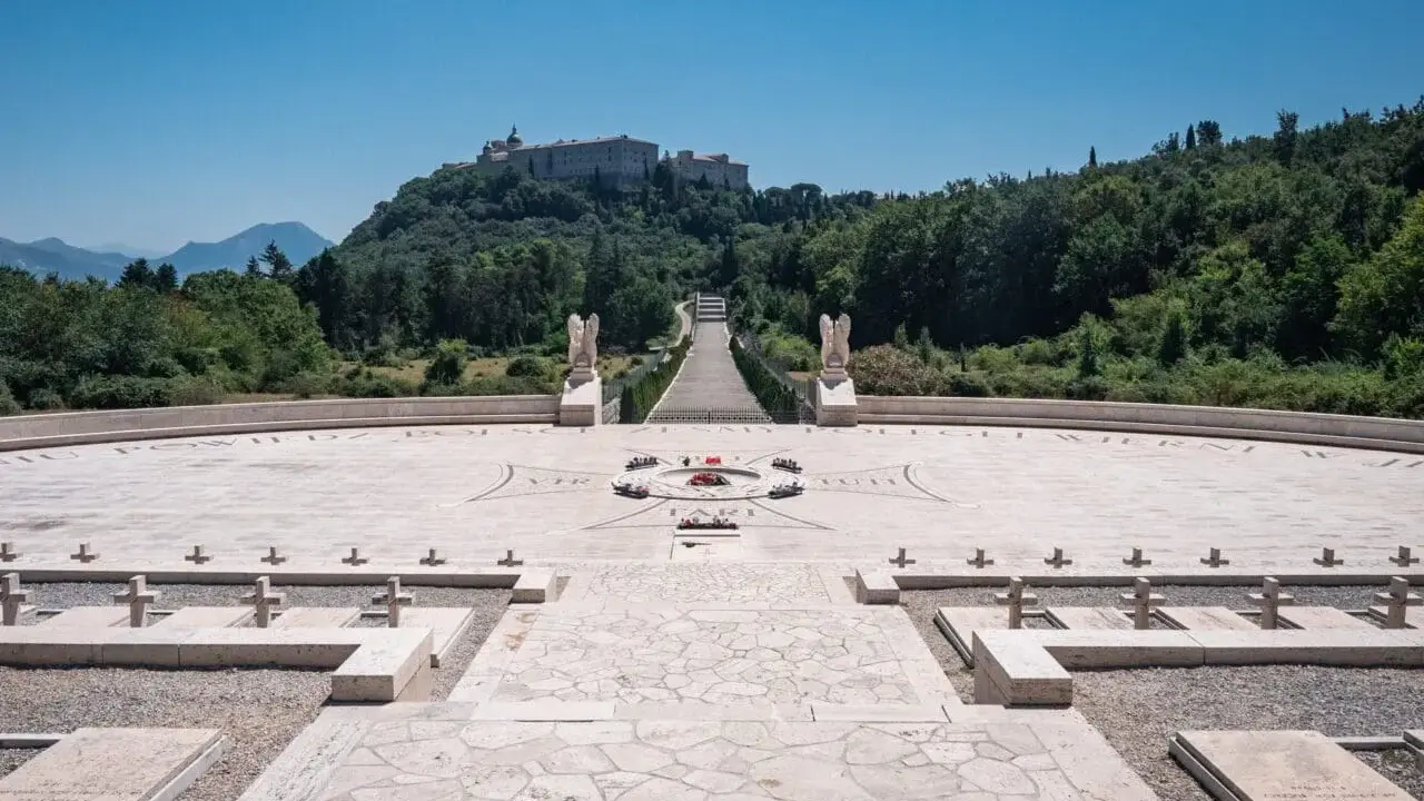 Cmentarz żołnierzy polskich, gdzie jest Monte Cassino. Monumentalny widok na wzgórze z opactwem, schody, krzyże i kamienne nagrobki.