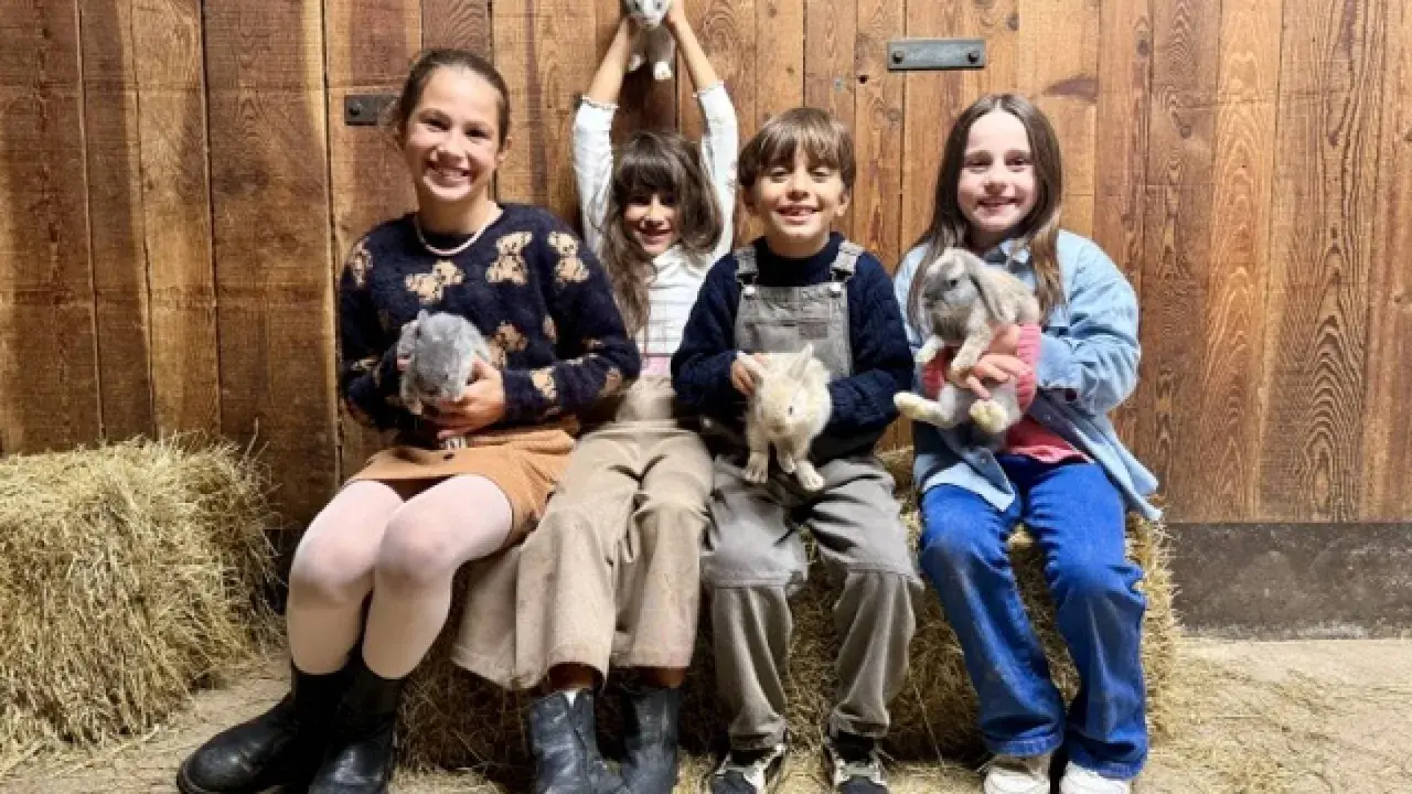Bambini felici durante un'attività fattoria, tengono in braccio coniglietti soffici.