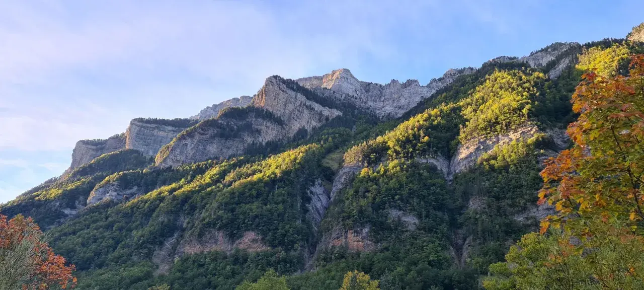 Majestuosas montañas cubiertas de bosque verde y rocas, perfectas para **rutas por Ordesa** en un día soleado.