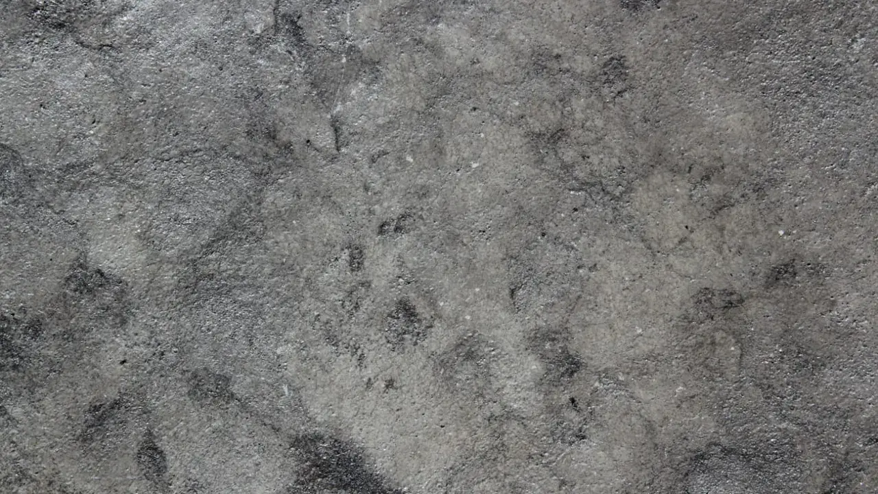 Textura rugosa y desigual de hormigón gris, con zonas más oscuras que sugieren desgaste o humedad.
