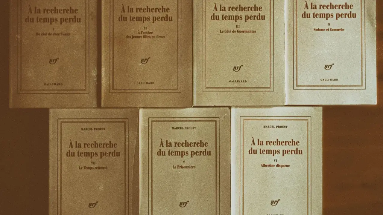 Una collezione di volumi di "Alla ricerca del tempo perduto" di Marcel Proust, editi da Gallimard, disposti su uno sfondo marrone.