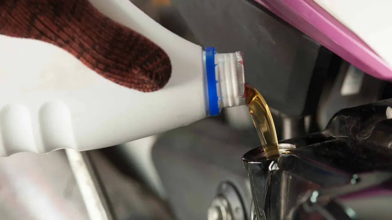 Rękawica nalewa nowy olej do silnika motocykla podczas wymiany oleju.
