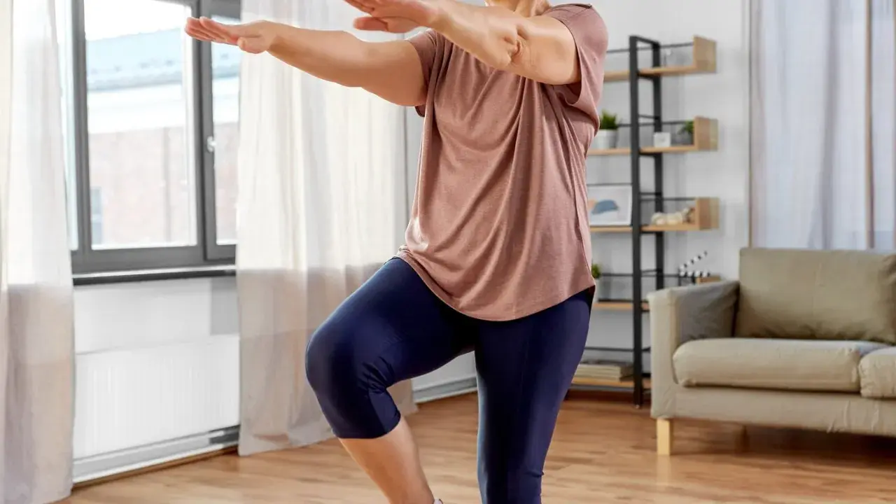 Frau macht Oberschenkel Training ohne Kniebelastung. Sie steht auf einem Bein, das andere angewinkelt.