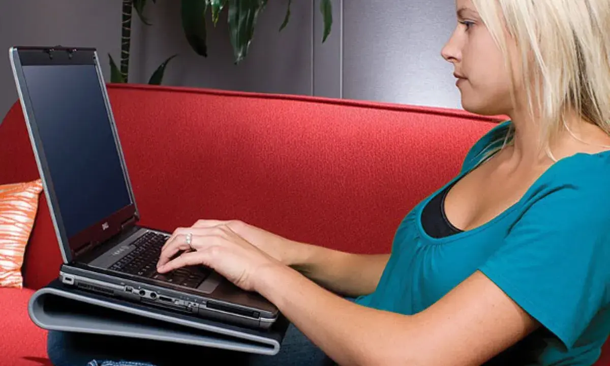 Une femme blonde effectue un entretien PC sur un canapé rouge.