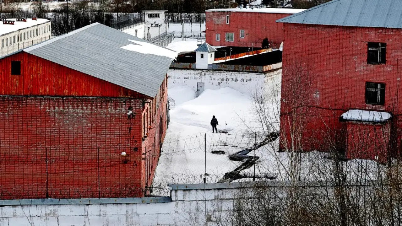 Zimowy dzień w kolonii karnej. Samotna postać wędruje po zasypanym śniegiem dziedzińcu, otoczonym ceglanymi budynkami i drutem kolczastym.