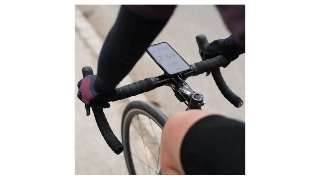 Rowerzysta trzyma kierownicę, na której zamontowano telefon za pomocą uchwytu sp connect. Na ekranie widoczny czas i prędkość.