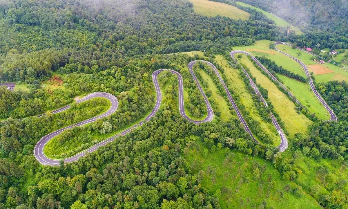 W serpentynach dróg w górach sanocko-turczańskich, wśród bujnej zieleni lasów i łąk, podróżują samochody.