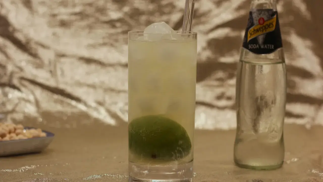 Erfrischender Drink mit Limette und Eis, daneben eine Flasche Schweppes Soda Water. Was ist Soda? Kohlensäurehaltiges Wasser, das für Cocktails verwendet wird.