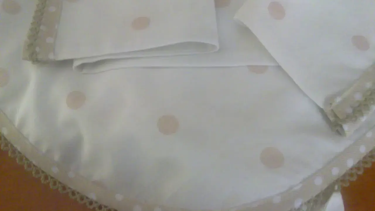Patrones de sábanas para cochecito de bebé hechas a mano con lunares rosados y borde de encaje.