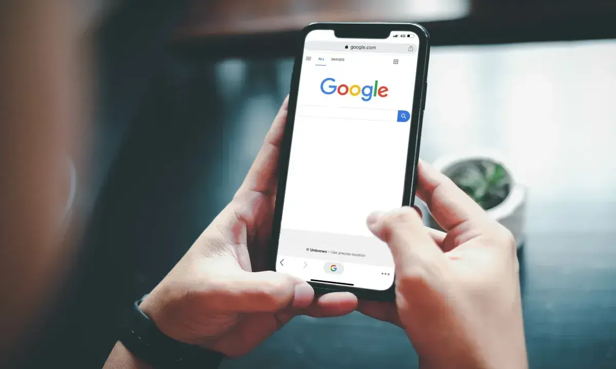Ręce trzymające smartfon z otwartą wyszukiwarką Google. Szukasz informacji, jak usunąć konto Google z telefonu po resecie?