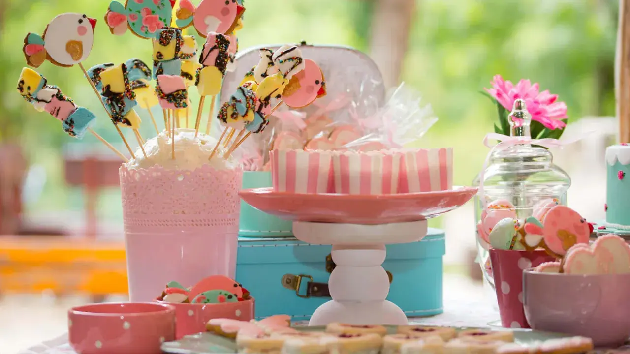 Una encantadora mesa de chuches casera con galletas de pájaros, malvaviscos y dulces en tonos pastel.