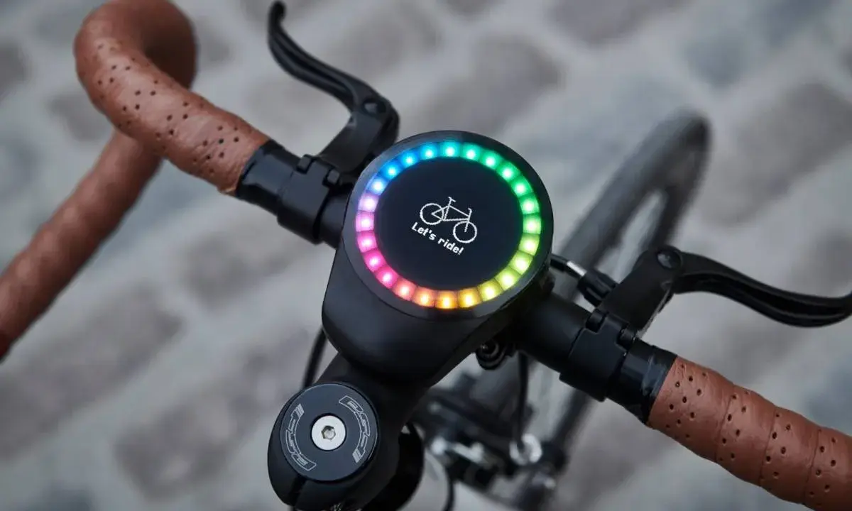 Nowy, okrągły wyświetlacz na kierownicy roweru z tęczowym podświetleniem i napisem "Let's ride!". Idealny do pomiaru prędkości, dystansu i innych parametrów, jak sigma rozmiar koła.