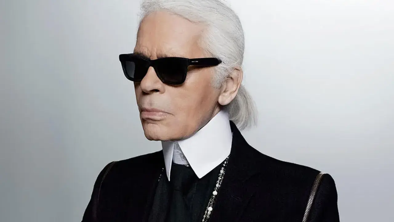 Ikona stylu, Karl Lagerfeld, w czarnym garniturze i okularach. Kto to? Ikona mody.