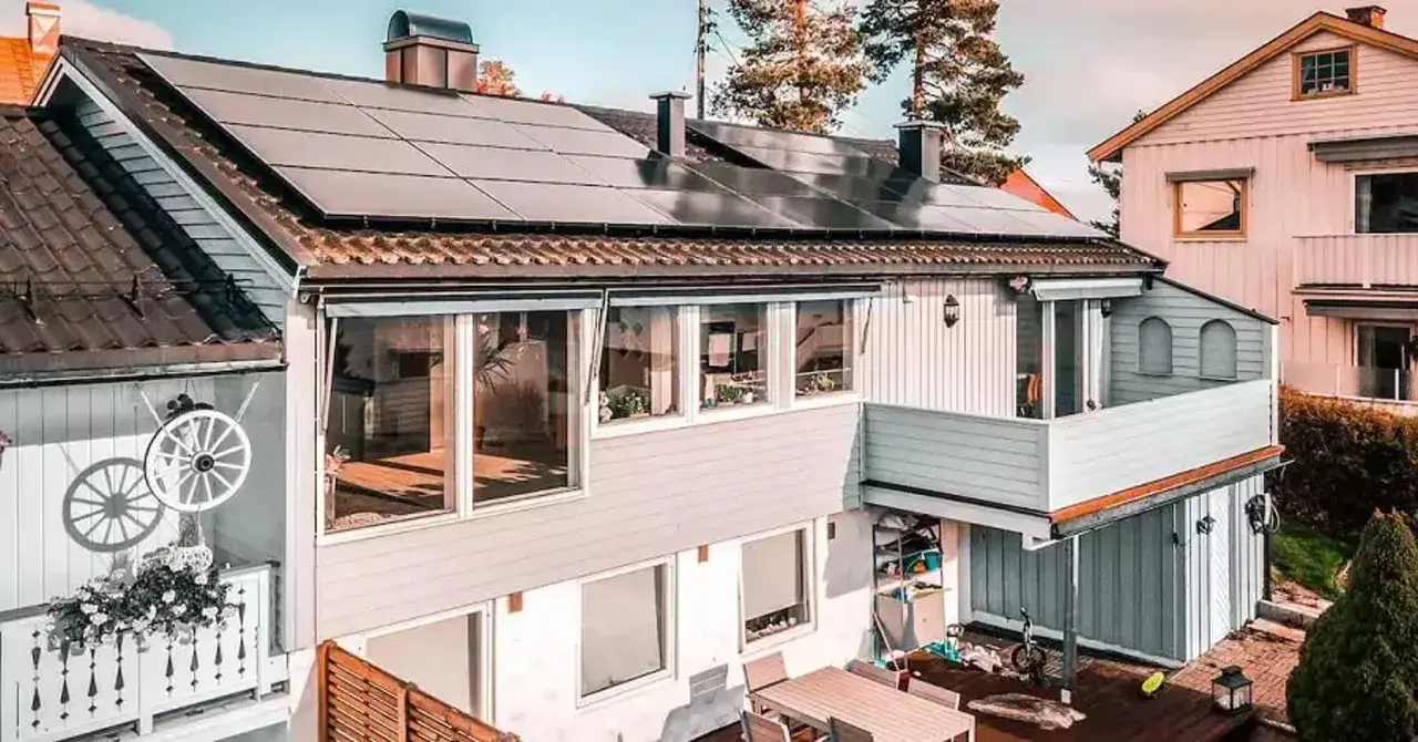 Hus med trina solceller på taket. En balkong med blommor och ett dekorativt hjul.