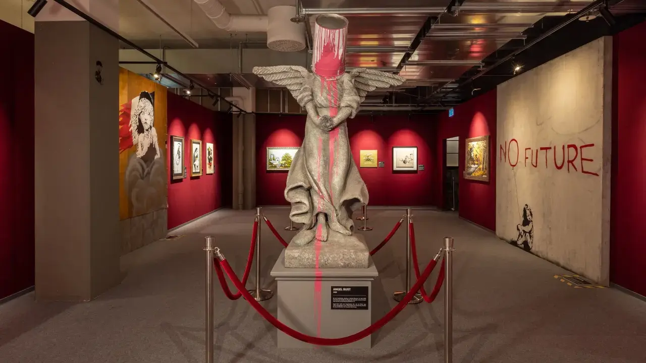 Banksy-utställning i Stockholm med en skulptur av en ängel med en färgburk på huvudet och texten "NO FUTURE".