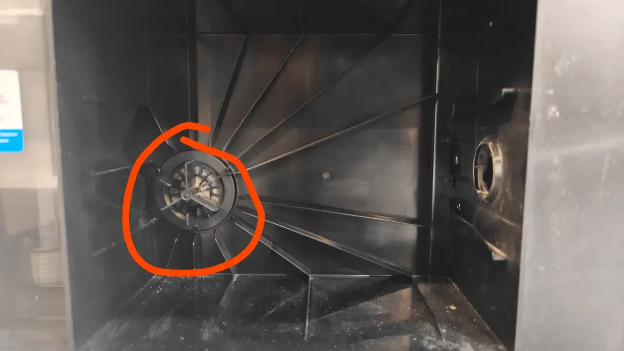 Der Staubbehälter eines Ecovacs Saugroboters, bereit zum Wechseln des Staubbeutels. Der Lüfter ist mit Staub bedeckt.