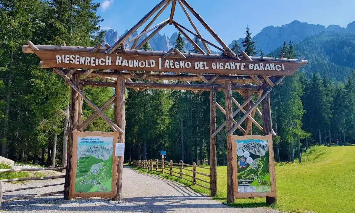 Ingresso in legno per il "Regno del Gigante Baranci", con cartelli informativi e sentiero che si addentra nel bosco.