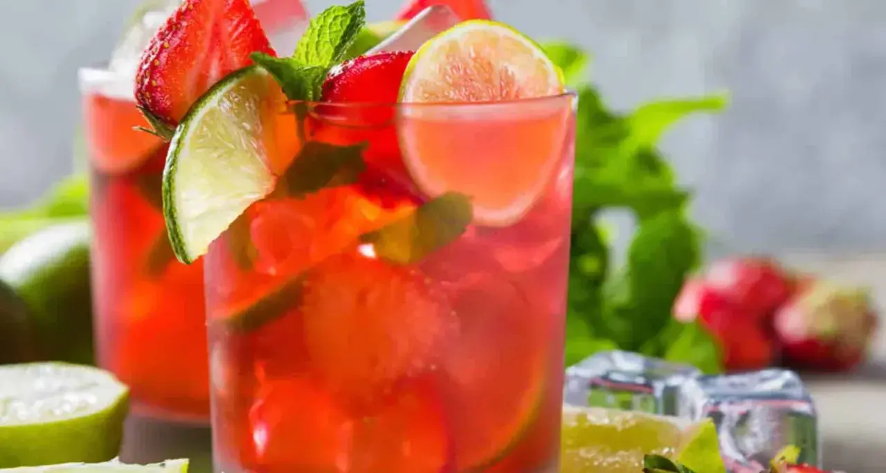 Två glas med en uppfriskande strawberry mojito, garnerade med jordgubbar, lime och mynta. Perfekt för en varm sommardag.