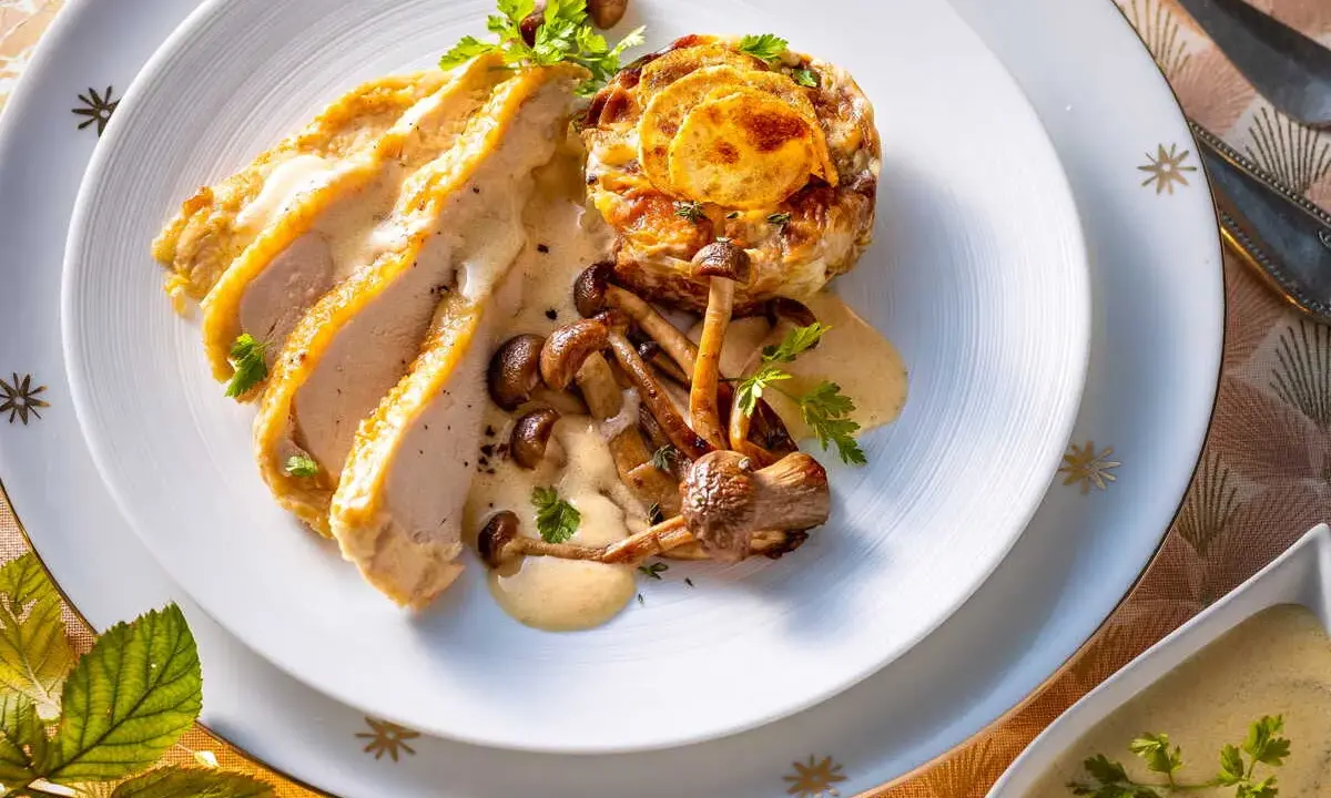 Délicieux poulet de Bresse à la crème, servi avec des champignons et une garniture dorée. Une recette qui éveille les papilles.