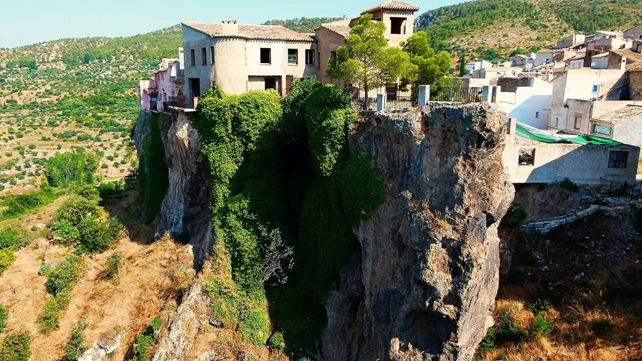 Casas aferradas a un acantilado, con vegetación cubriendo la roca. El mirador de la Molatica ofrece vistas espectaculares del paisaje.
