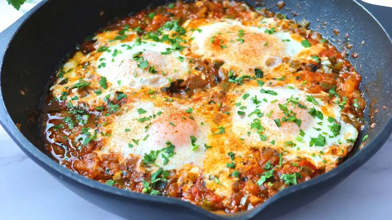Huevos pochados en salsa de tomate y pimientos, un plato perfecto para tus recetas con huevos. Espolvoreado con perejil fresco.
