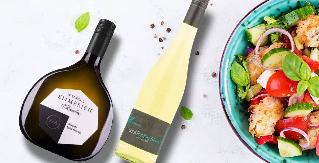 Zwei Flaschen Wein, eine davon eine Scheurebe aus Franken, neben einem bunten Salat.