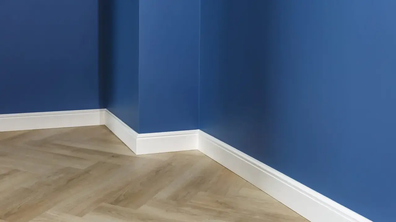 Un coin de pièce aux murs bleu profond, avec un parquet imitation bois clair et un élégant type de plinthe blanc.
