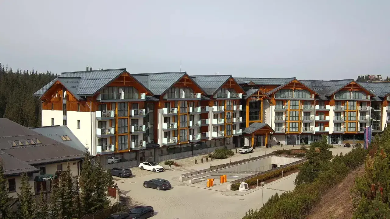 Widok z kamer w Bukowinie Tatrzańskiej na nowoczesny hotel z drewnianymi elementami i parkingiem.
