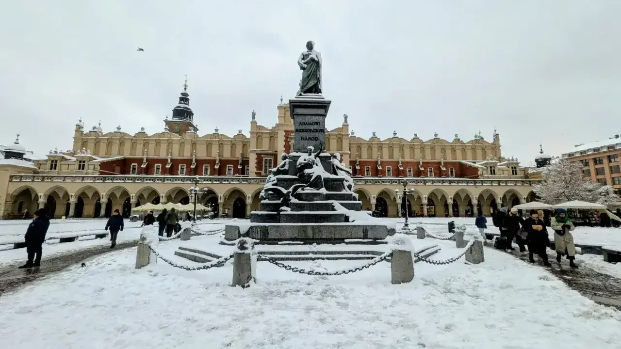 Zimowy weekend w Krakowie. Rynek Główny ze Sukiennicami i pomnikiem Adama Mickiewicza, pokryty śniegiem.