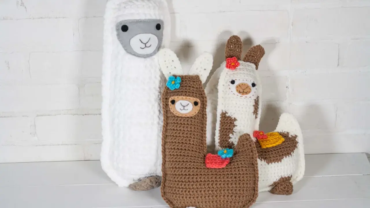 Un grupo de adorables llamas amigurumi, hechas a mano con lana, posan juntas.