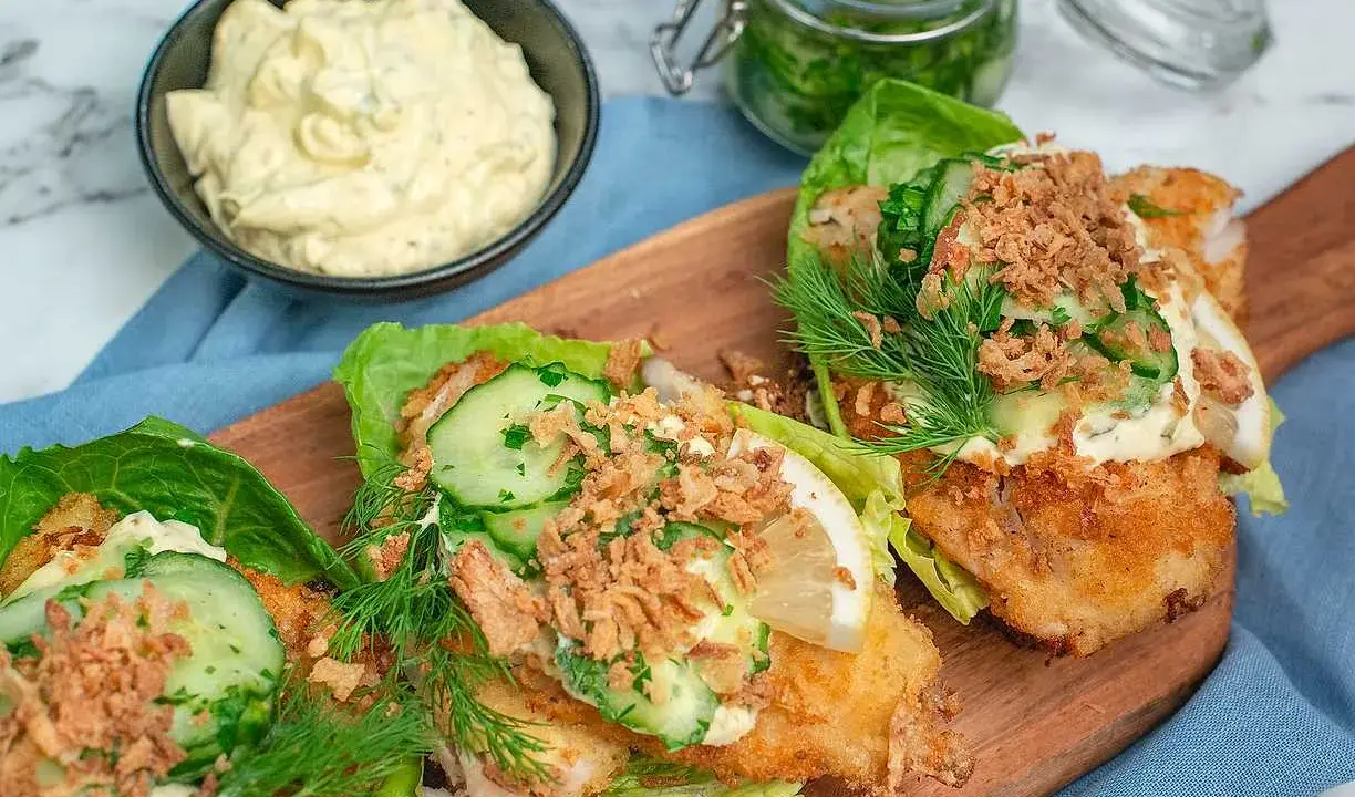 Friterad fisk i salladsblad med gurka, dill och krispiga lökar. En skål med krämig remouladsås, perfekt för ditt remouladsås recept.