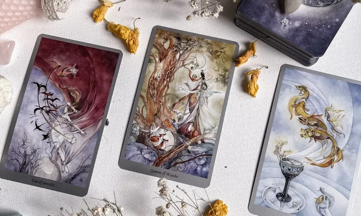 Trzy karty tarota: Dziesiątka Mieczy, Królowa Buław i As Kielichów, tworzą magiczną atmosferę. Idealne do wróżenia, jak tarot online, który się sprawdza.