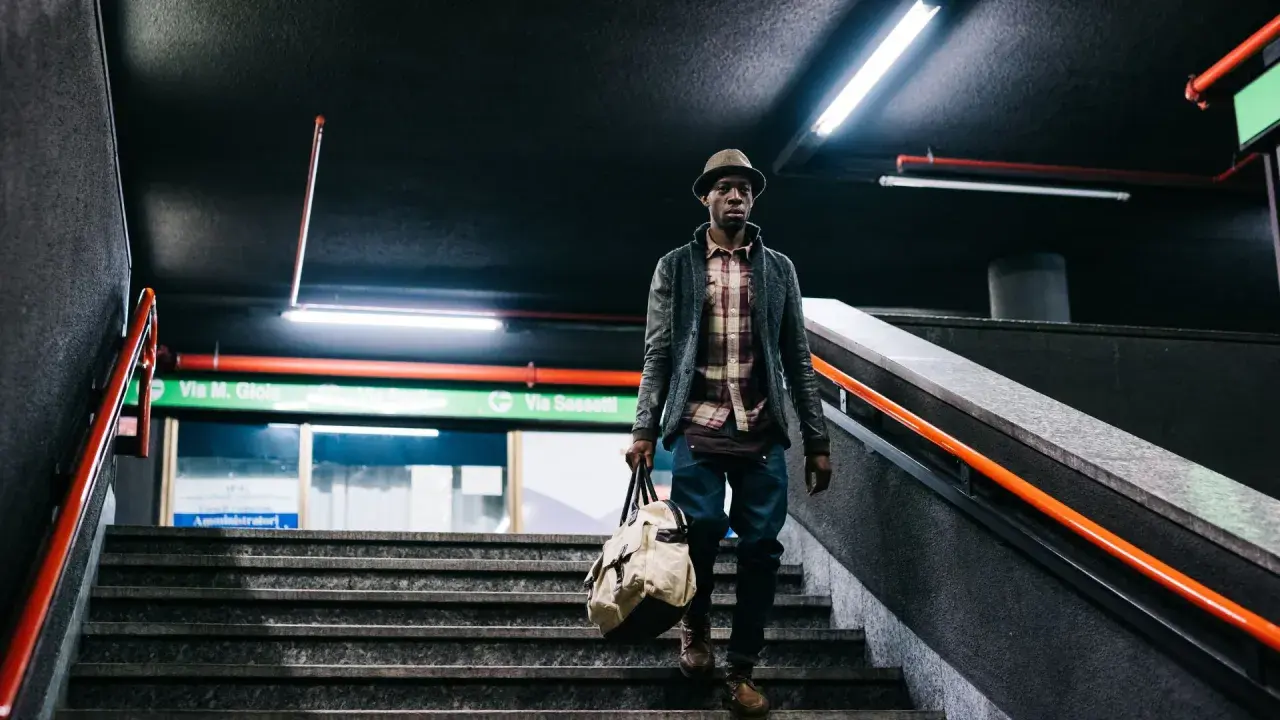 Uomo con borsa scende le scale di una metropolitana, un'immagine con un'atmosfera urbana e moderna. Queste foto creative catturano momenti di vita quotidiana.