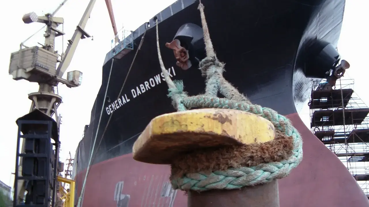 Gros plan sur une aussière, définition de l'amarrage d'un navire, le "GENERAL DABROWSKI", au port. Grues et échafaudages en arrière-plan.