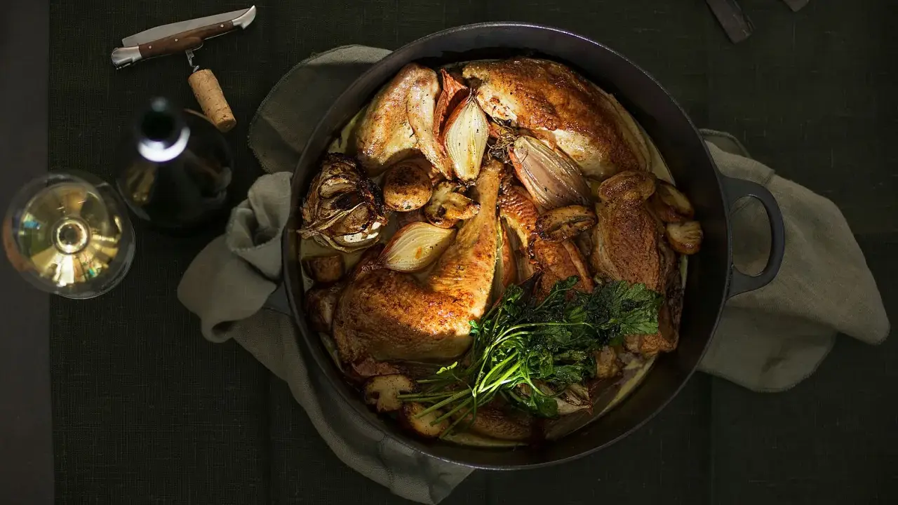 Ein Brathähnchen mit Zwiebeln und Kräutern, bereit zum Genuss. Dazu ein Glas Wein, der den Riesling Geschmack unterstreicht.
