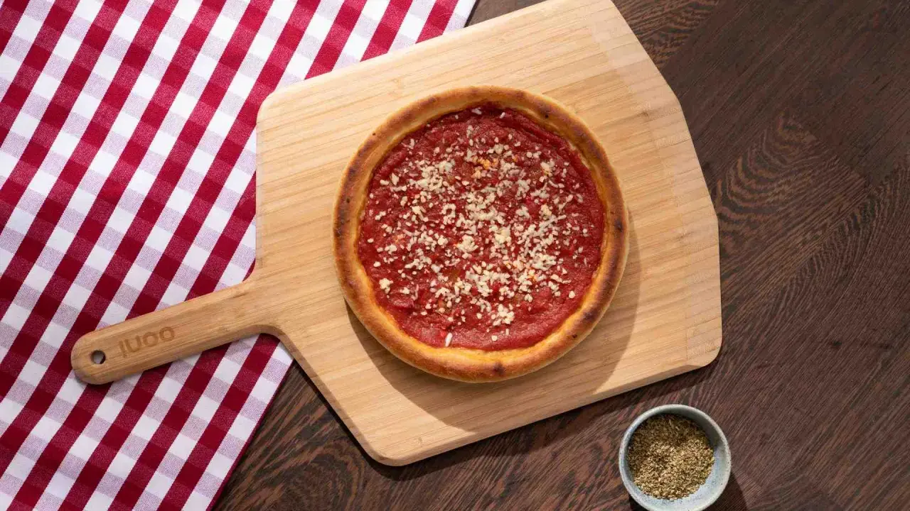 Pizza sur planche en bois, avec une nappe à carreaux rouges et blancs. La proportion levain farine eau est parfaite pour cette croûte dorée.