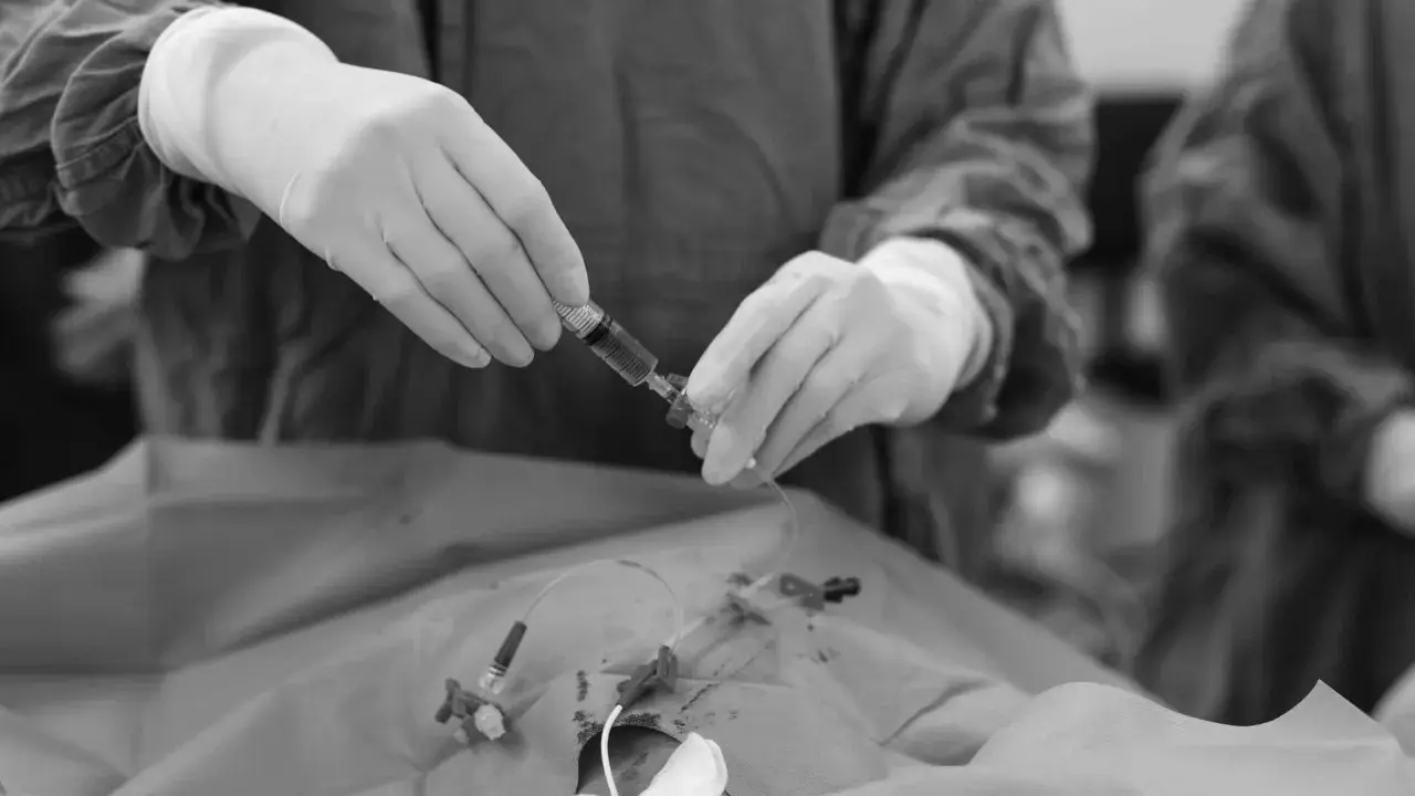Mani guantate preparano una siringa per la picc chemio, un momento delicato di cura.