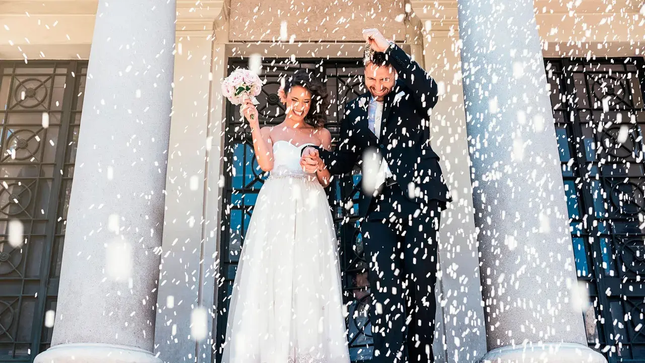Novios felices bajo confeti. Inspiración para textos para bodas, capturando la alegría del momento.